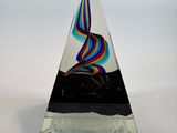 a glass sculpture of a rainbow swirl on a black base