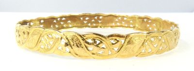 une image d'un gros plan d'un bracelet en or sur une surface blanche