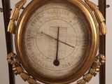 a gold clock on a wooden stand with a clock face