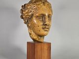 un gros plan d'une sculpture représentant une tête de femme posée sur un socle en bois