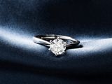 un gros plan d'une bague en diamant sur un fond de satin bleu