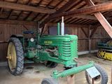 un tracteur vert dans une grange au toit en bois