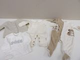 many baby clothes laid out on a white table