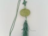 un collier auquel est suspendu un pompon vert sur le côté