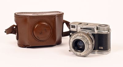 un appareil photo marron et un étui marron posés sur une surface blanche