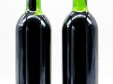 two bottles of wine sitting next to each other on a white surface