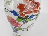 a white vase with flowers painted on it on a table