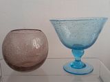 two vases sitting on a glass shelf next to each other