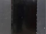an image of a black refrigerator against a grey wall