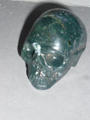 a green stone skull sitting on a white surface