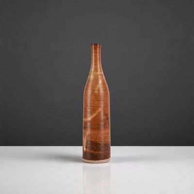 un vase marron posé sur une table près d'un mur noir