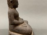 an old statue of a person sitting on top of a rock