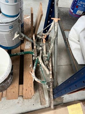 several buckets of paint sitting on top of a pallet next to a pile of wood