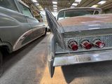two old cars parked in a garage next to each other