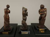 three bronze statues of a woman and a man on a black pedestal