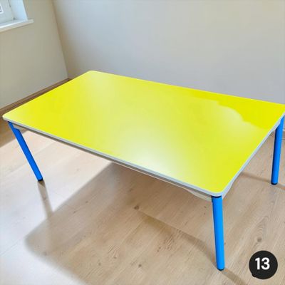 une table jaune aux pieds bleus dans une pièce