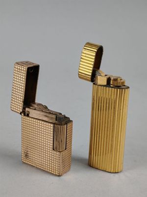 deux briquets dorés posés l'un à côté de l'autre sur une surface grise
