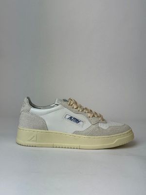 the white and blue sneakers are sitting on a white surface
