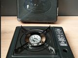 un réchaud à gaz portable posé sur une table à côté d'une valise