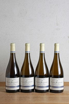 quatre bouteilles de vin sont alignées sur une table en bois