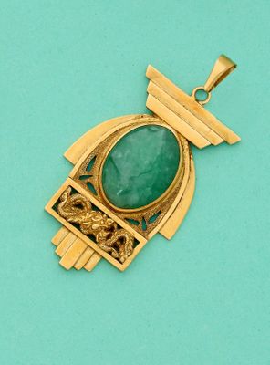 un gros plan d'un pendentif en or orné d'une pierre verte