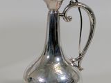 an image of a silver pitcher with a handle on a white surface