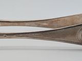 a silver spoon with a flower on it on a white surface
