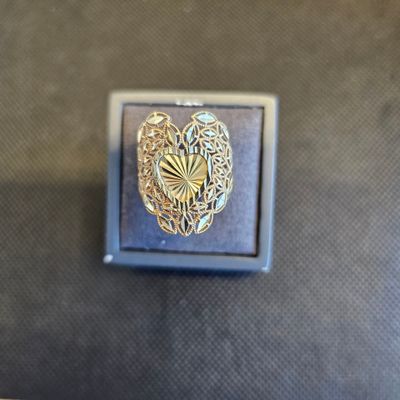 une photo d'une broche en forme de cœur dorée posée sur un écrin noir
