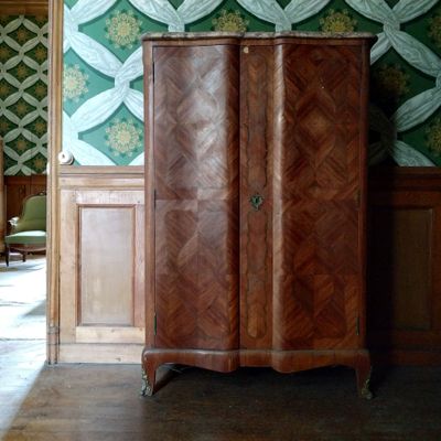 une armoire au milieu d'une pièce dont l'un des murs est tapissé