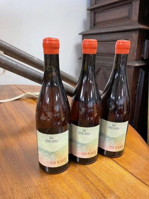 three bottles of wine sitting on a table next to a lamp