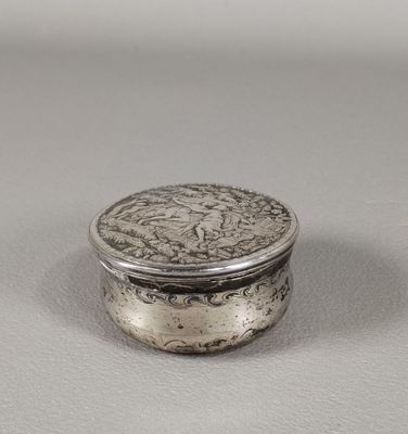 une boîte en argent contenant une pièce, posée sur une surface blanche