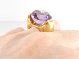 someone is holding a ring with an amethorate stone in it