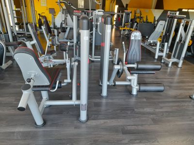 des rangées d'appareils de musculation dans une salle de sport aux murs jaunes
