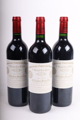 trois bouteilles de vin rouge posées l'une à côté de l'autre sur une surface blanche