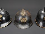three helmets of different sizes and colors on a gray surface