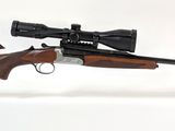 le fusil est posé sur un support transparent et est équipé d'une lunette de visée