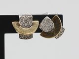 two gold and silver earrings with diamonds on a black stand