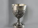 a silver goblet sitting on a table with a gray background