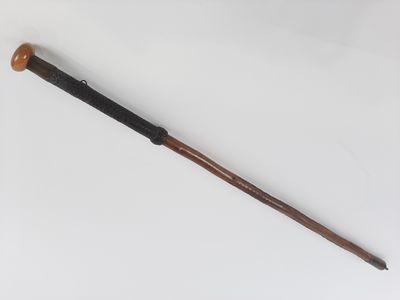 une vieille batte de baseball avec un manche en bois posée sur une surface blanche
