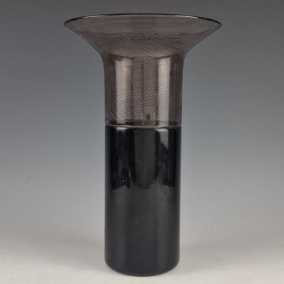a glass vase with a black base sitting on a table