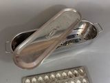 a silver container with a spoon in it next to a tray of eggs