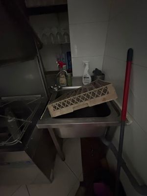 a metal sink in a small kitchen with a mop next to it