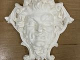 a white sculpture of a man ' s face on a wooden table