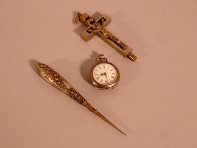 une petite montre de poche en or et un stylo posés sur une table