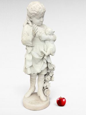 une statue représentant un garçon tenant un bébé et une pomme