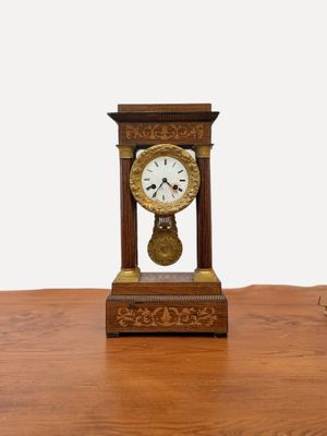 une petite horloge en bois posée sur une table, sur fond blanc