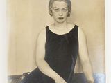 an old photo of a woman in a black dress sitting on a table