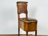 chaise en bois avec assise en cuir, posée sur un parquet