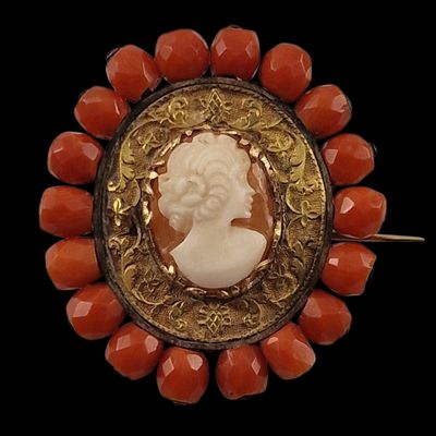 an image of a red and gold broochle with a woman ' s profile