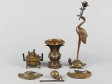 an assortment of brass objects including a bird, a candle, a bowl, and a spoon
